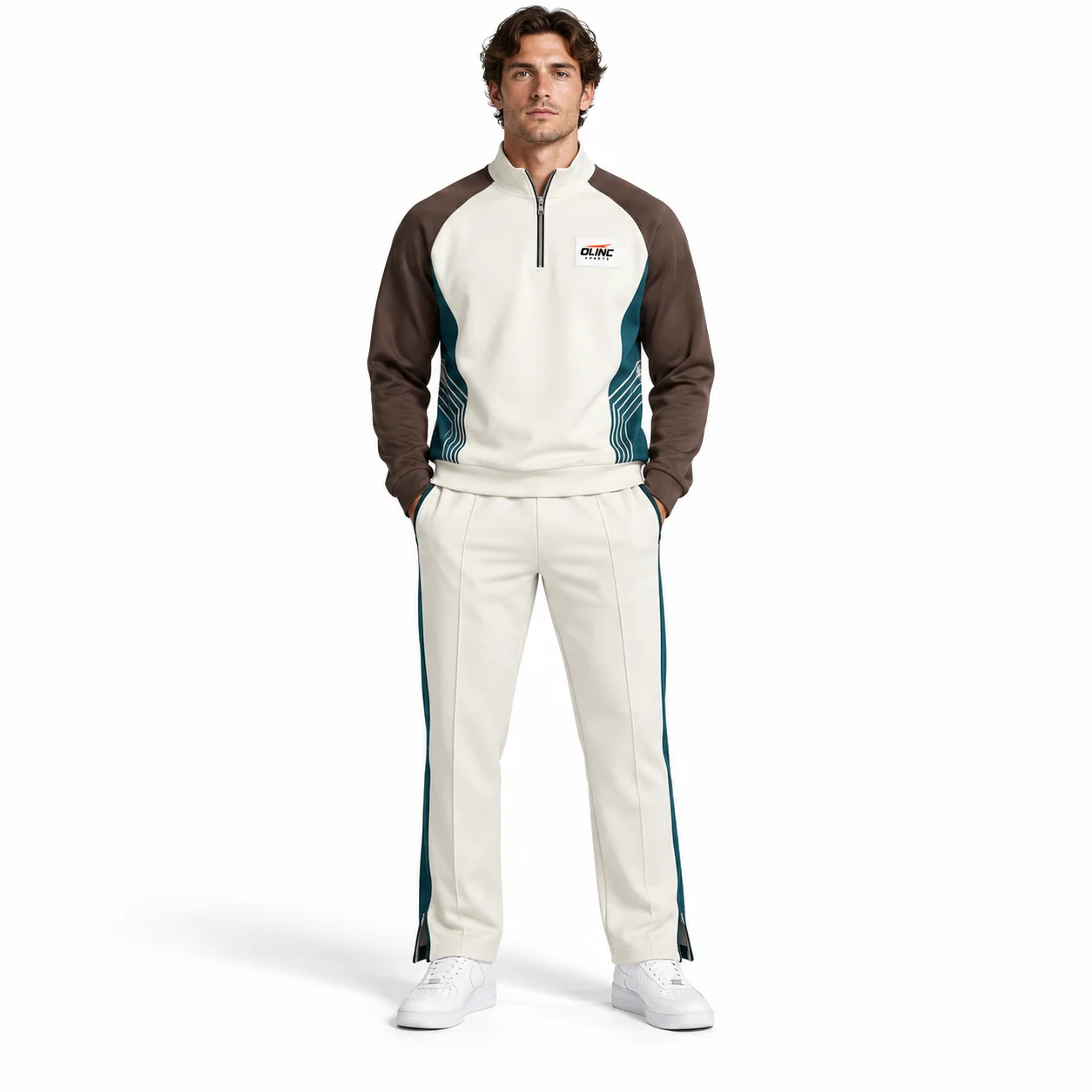 Tracksuit Crestline Half-Zip Set front design view showing bone top, steel-brown raglan sleeves and deep-teal side inserts; bone straight-leg trousers with deep-teal outer-leg panels